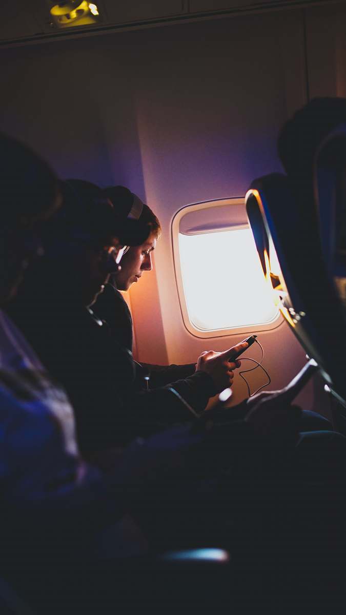 airplane passenger photo of three people listening to music inside airplane on an airplane
